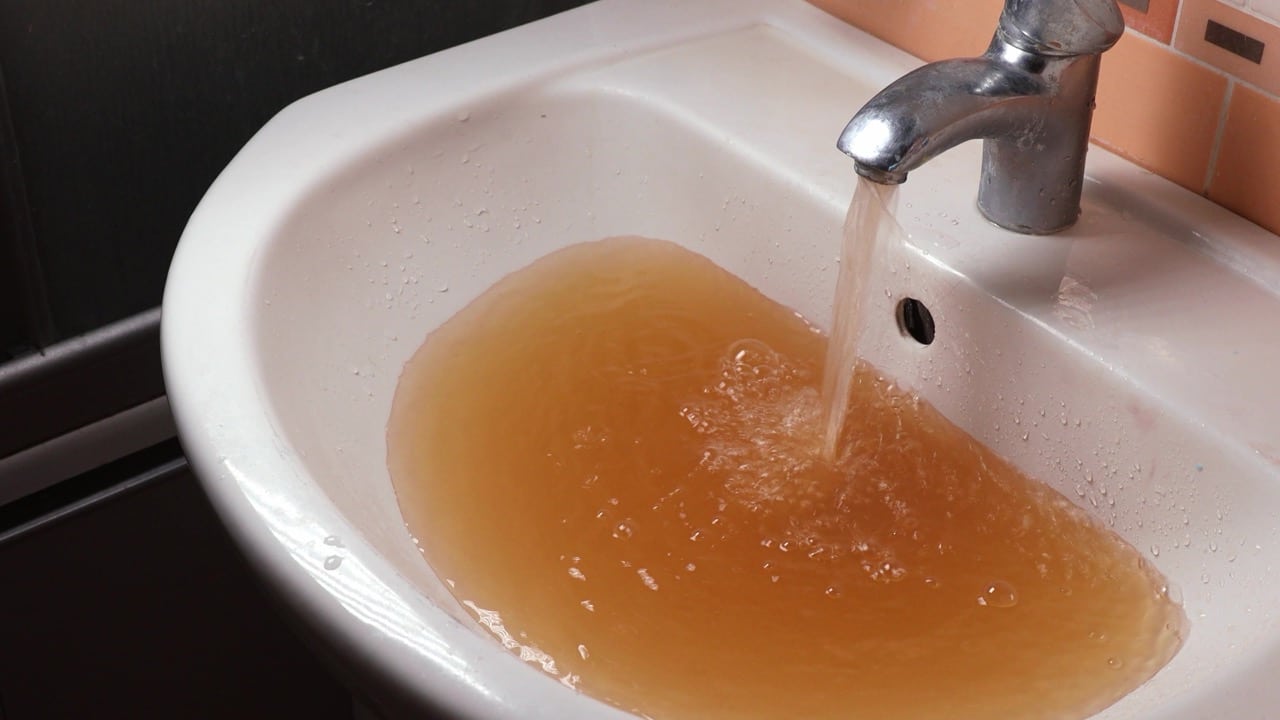 Discolored water filling a bathroom sink from a compromised water line