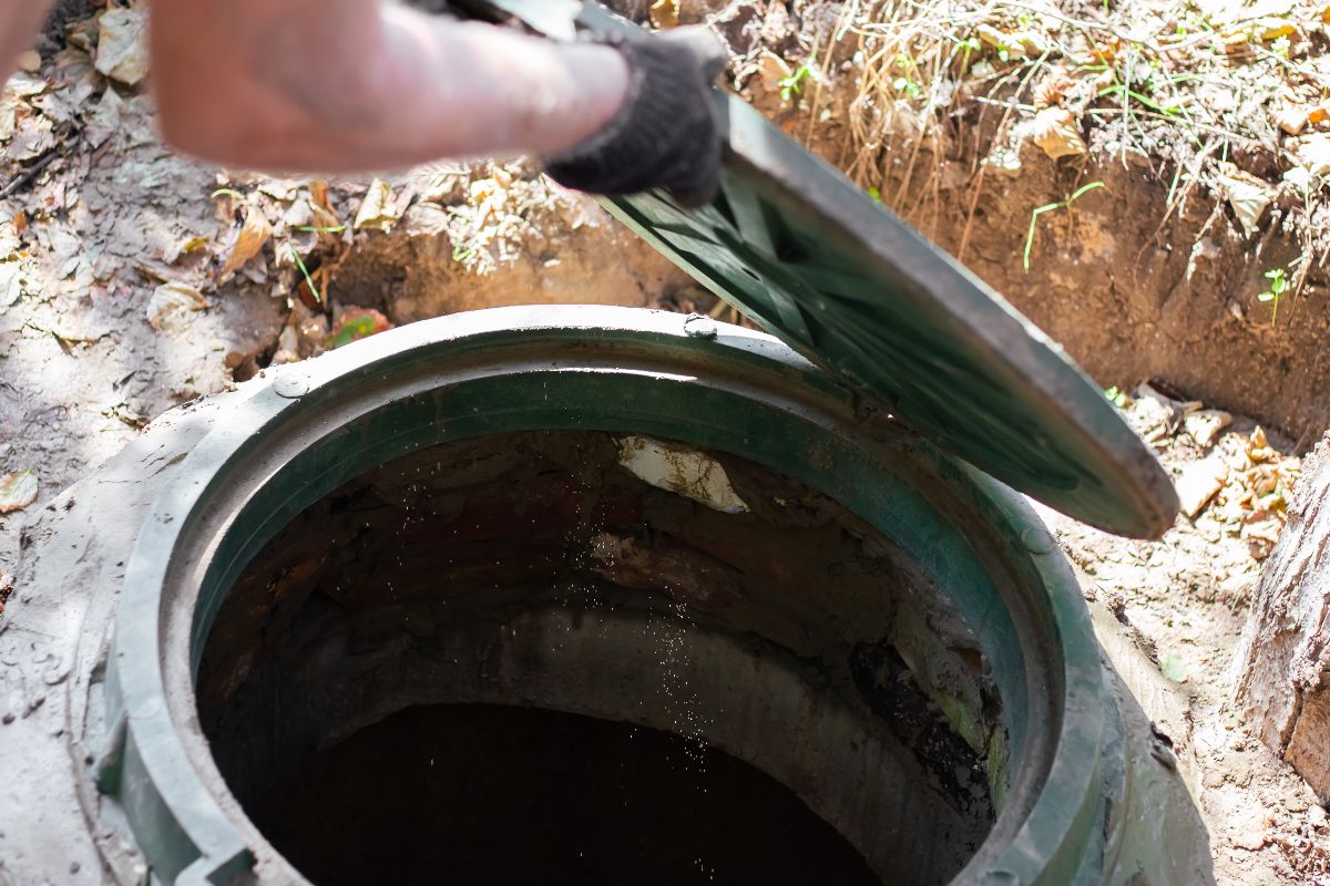 close up of man opening sewer hatch to a septic tank