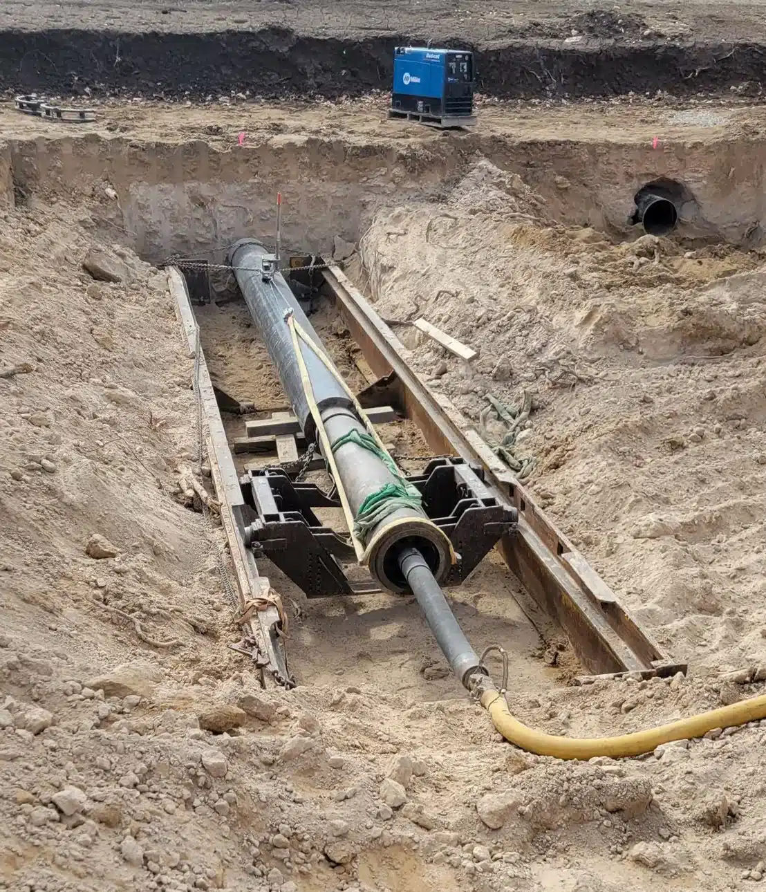 Crew member connecting a water line at the bottom of a trench